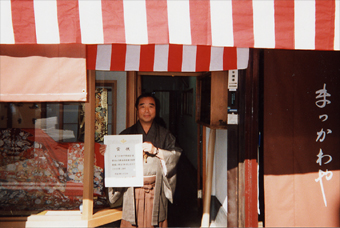 店の前にて、賞状を手に満面の笑顔の店主